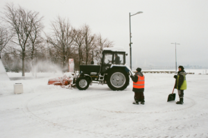 two men standing by snow removal tractor